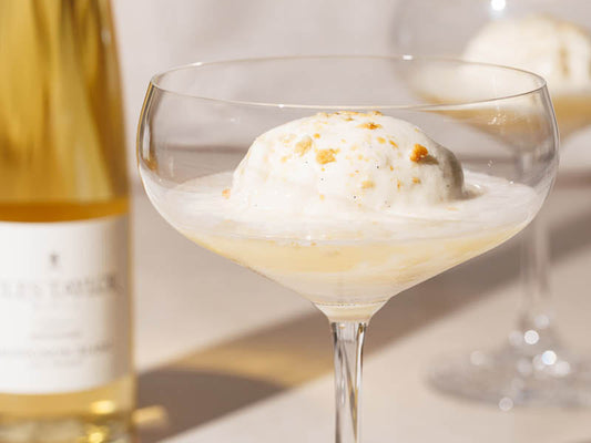 A coupe of ice cream with Jules Taylor Late Harvest Sauvignon poured over, with a blurred bottle of wine in the background.