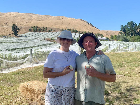 Jules Taylor and Jeremy Hyland standing in a Marlborough vineyard with nets on the vines